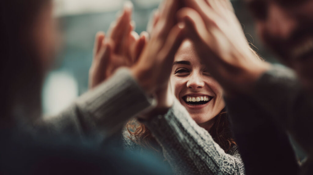Equipo de trabajo celebrando con un choca los cinco para fomentar el apoyo emocional y la salud mental en la oficina.