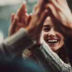 Equipo de trabajo celebrando con un choca los cinco para fomentar el apoyo emocional y la salud mental en la oficina.